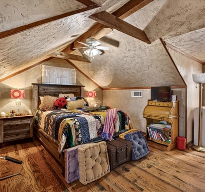 Cozy attic bedroom featuring unique rustic decor, ample natural light, and inviting wooden accents throughout.