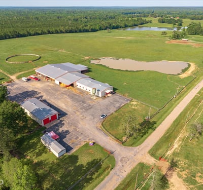 Spacious rural property featuring vast open fields, a pond, and extensive outbuildings for multiple uses.