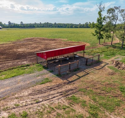 Versatile property featuring a spacious open field with a covered structure, perfect for agricultural or recreational use.