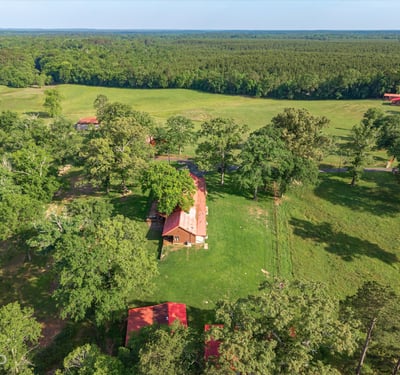 Spacious property featuring a cozy home surrounded by lush greenery and expansive fields, perfect for outdoor enthusiasts.