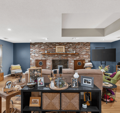 Spacious living area featuring exposed brick accents, ample natural light, and versatile entertainment options.