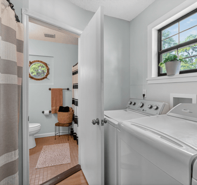 Bright and functional laundry area seamlessly connecting to a full bathroom.