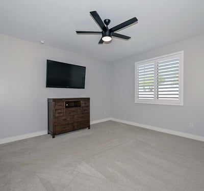 A peaceful primary suite with soft gray tones, upgraded ceiling fan, and bright natural light designed for restful living in this Peoria home.