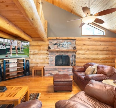 Stunning stone fireplace paired with vaulted ceilings and log construction, creating a cozy yet dramatic focal point in the main living area.