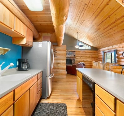 Functional kitchen design with wood cabinetry, stainless steel refrigerator, and clear views into the great room for easy entertaining.