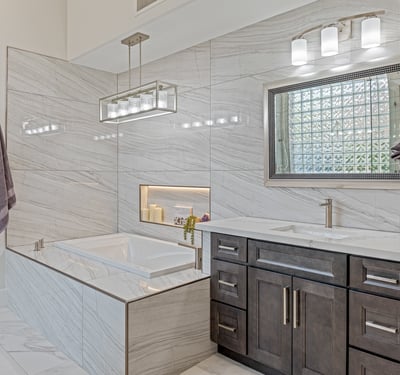 Luxurious soaking tub with marble surround, built-in bench, and dual vanities provide comfort and sophistication.