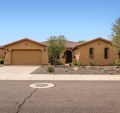 Front elevation with mature trees, desert landscaping, and a two-car garage creates an attractive first impression in this Peoria property.