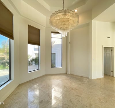 Elegant dining room featuring a stunning chandelier, soaring ceilings, and tall windows that fill the space with warmth and sophistication.