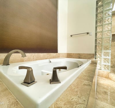 Luxurious soaking tub surrounded by elegant marble tile and designer fixtures, creating a tranquil retreat within this Scottsdale home.