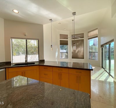 Modern kitchen with granite island, pendant lights, and abundant windows that create a cheerful dining environment.