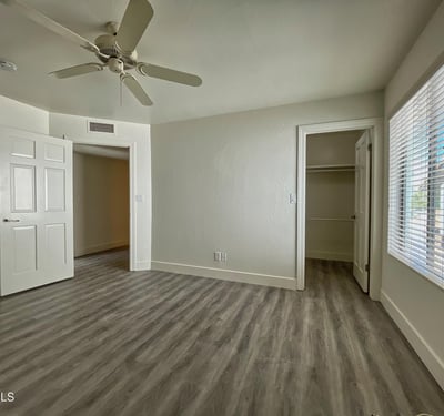 Relaxing bedroom with soft neutral tones, ceiling fan, and ample closet storage, offering comfort and tranquility.