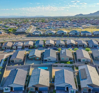 Wide-angle drone view capturing surrounding homes, open spaces, and mountain silhouettes. The area delivers a blend of beauty and convenience.