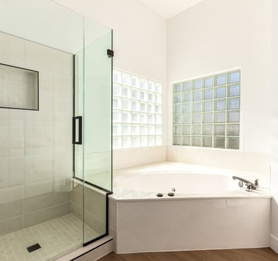 Relaxing Scottsdale bathroom featuring a glass walk-in shower and large soaking tub surrounded by natural light from glass block windows. Modern finishes create a luxurious atmosphere.