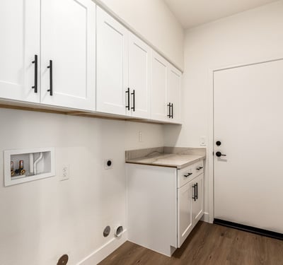 Well-designed Scottsdale laundry room featuring overhead cabinets, counter space, and washer/dryer hookups. The organized layout provides convenient storage and everyday functionality for household tasks.