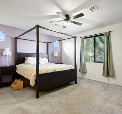 Primary bedroom featuring soft carpet, ceiling fan, and generous floor space, creating a relaxing and private sleeping area.