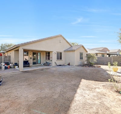 Rear view of the home showing a covered patio and open yard, offering versatile outdoor living and entertaining possibilities.