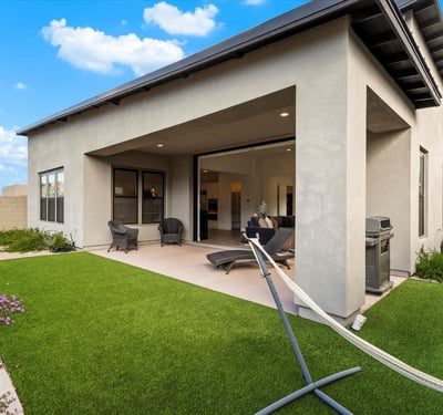 Thoughtfully designed backyard with turf, patio seating, and modern exterior lines. A perfect retreat in this Scottsdale luxury home.