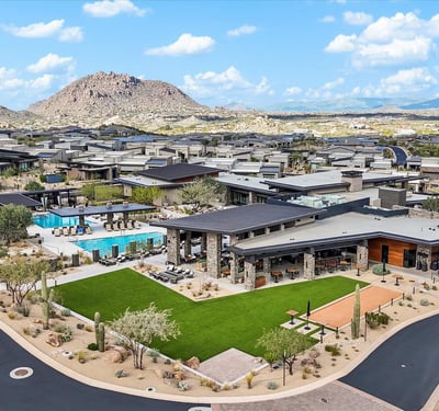 Aerial showcase of the Sereno Canyon clubhouse featuring resort-style pools, modern design, and expansive mountain scenery within a guard-gated Scottsdale community.