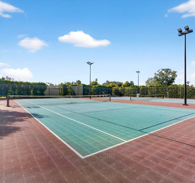 Community tennis courts surrounded by mature landscaping, offering a convenient recreational option just moments from home.