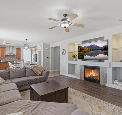 Stylish living area featuring a fireplace with decorative niches, ceiling fans, and durable wood-style flooring throughout the main living space.