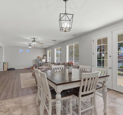 Dining area with elegant pendant lighting and French doors providing access to the backyard pool and outdoor living area.