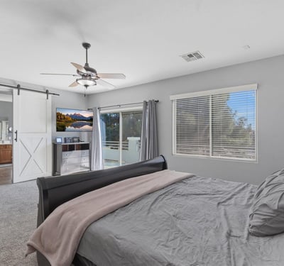 Spacious primary bedroom with plush carpet, ceiling fan, and neutral tones, offering a relaxing retreat within this well-designed Queen Creek home.