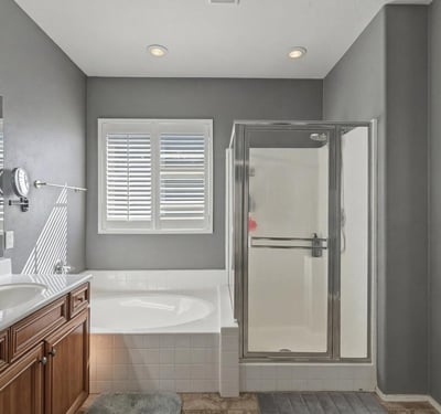 Spacious primary bathroom featuring a soaking tub, separate glass shower, and tile flooring designed for comfort and convenience.