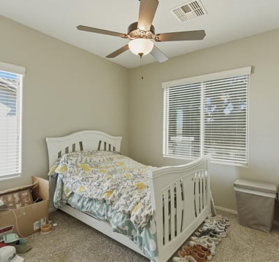 Comfortable secondary bedroom with plush carpet, ceiling fan, and large windows that bring in natural light, creating a welcoming space for guests or family.