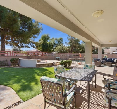 Shaded patio overlooking the landscaped yard and pool area, providing a comfortable outdoor living space for dining or relaxing.