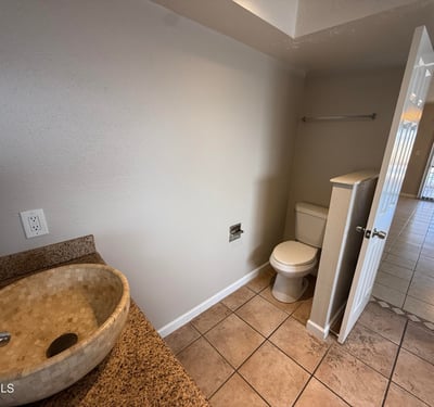 Bathroom layout highlighting a large soaking tub, granite vanity, and vessel sink. Natural lighting enhances the clean and spacious design of this Glendale home's primary bath.
