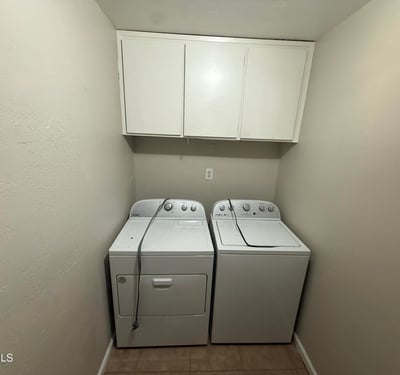 Laundry room featuring washer and dryer with built-in overhead cabinets for additional storage. Convenient layout helps keep daily household tasks organized.