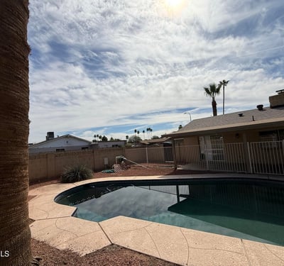 Inviting Pebble Tec pool surrounded by desert landscaping and privacy fencing. The outdoor space creates a refreshing retreat perfect for enjoying Glendale s warm weather.