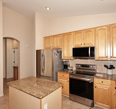 Kitchen with granite island, stainless appliances, and warm wood cabinetry. This Phoenix home provides functional prep space and a welcoming cooking area.