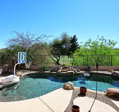 Resort-style pool area with rock features and panoramic golf course views. This Phoenix property delivers a peaceful outdoor setting perfect for enjoying Arizona living.