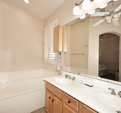 Primary bathroom with dual sinks, large mirror, and bright lighting. This Phoenix home offers convenience and comfort in a well-designed layout.