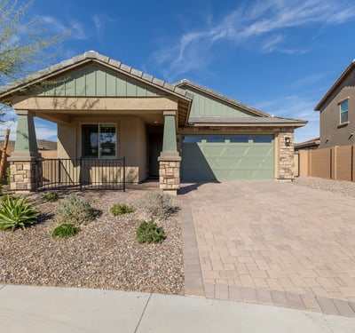 Stunning Peoria home exterior with paver driveway, stone detailing, and desert landscaping. Offers low-maintenance living and strong curb appeal.