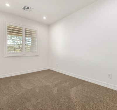 Well-lit bedroom with neutral tones and plush carpet, perfect for guests, family, or a flexible living space.