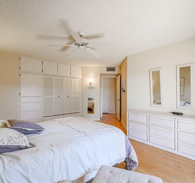 Secondary bedroom with built-in cabinets, hardwood floors, and ample closet space, ideal for guests or flexible living needs.