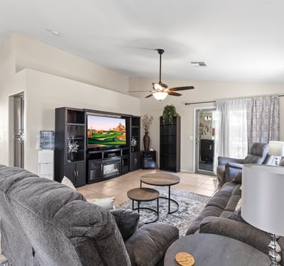 Comfortable family room with neutral finishes, ceiling fan, and open flow to kitchen and dining areas for easy living.