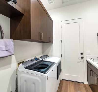 Efficient laundry space with built-in cabinets, sink, and modern washer and dryer, adding practicality to this Phoenix residence.