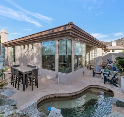Private backyard with multiple seating areas, stone patio, and desert landscaping designed for easy upkeep in Phoenix.
