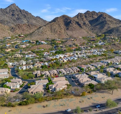 Aerial shot of homes near a manicured golf course with tree-lined streets and open green space in this Phoenix neighborhood.