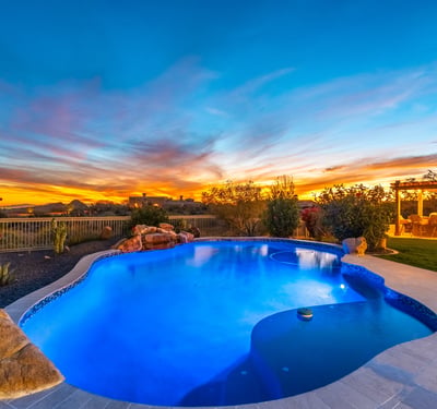 Scottsdale backyard illuminated at sunset with pool, spa, and outdoor kitchen, creating the perfect space for entertaining and relaxing evenings.