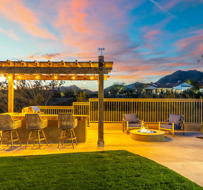 Stylish outdoor entertaining area with built-in kitchen, bar seating, and fire pit, set against scenic Scottsdale mountain views.