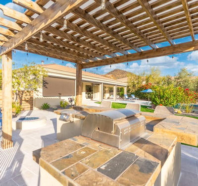 Scottsdale outdoor entertaining area with pergola, kitchen, and seating, offering a stylish and functional backyard retreat.