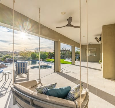 Scottsdale covered patio featuring modern hanging seating, ceiling fans, and open views to the pool and backyard.