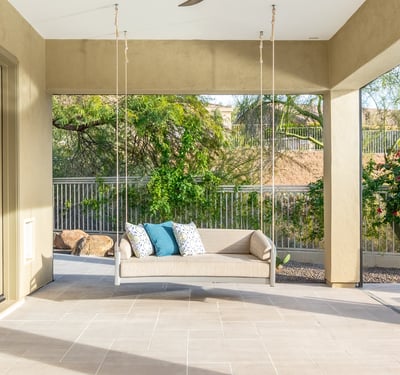 Scottsdale outdoor living space with hanging swing bench, tiled patio, and serene backyard views.