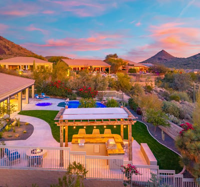 Scottsdale backyard featuring a pergola-covered outdoor kitchen with built-in grill and seating, perfect for entertaining with views of the pool and desert.