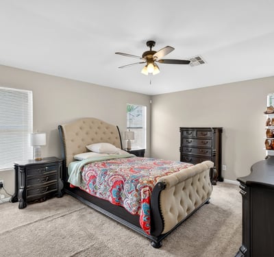 Generous primary bedroom with ceiling fan, soft carpet, and multiple windows. A relaxing retreat designed for comfort in this Casa Grande home.