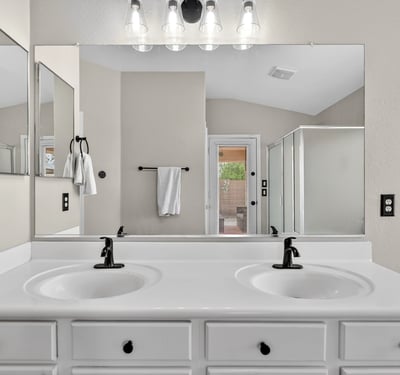 Spacious primary bathroom with dual vanities and modern fixtures. Functional layout enhances everyday convenience in Casa Grande.